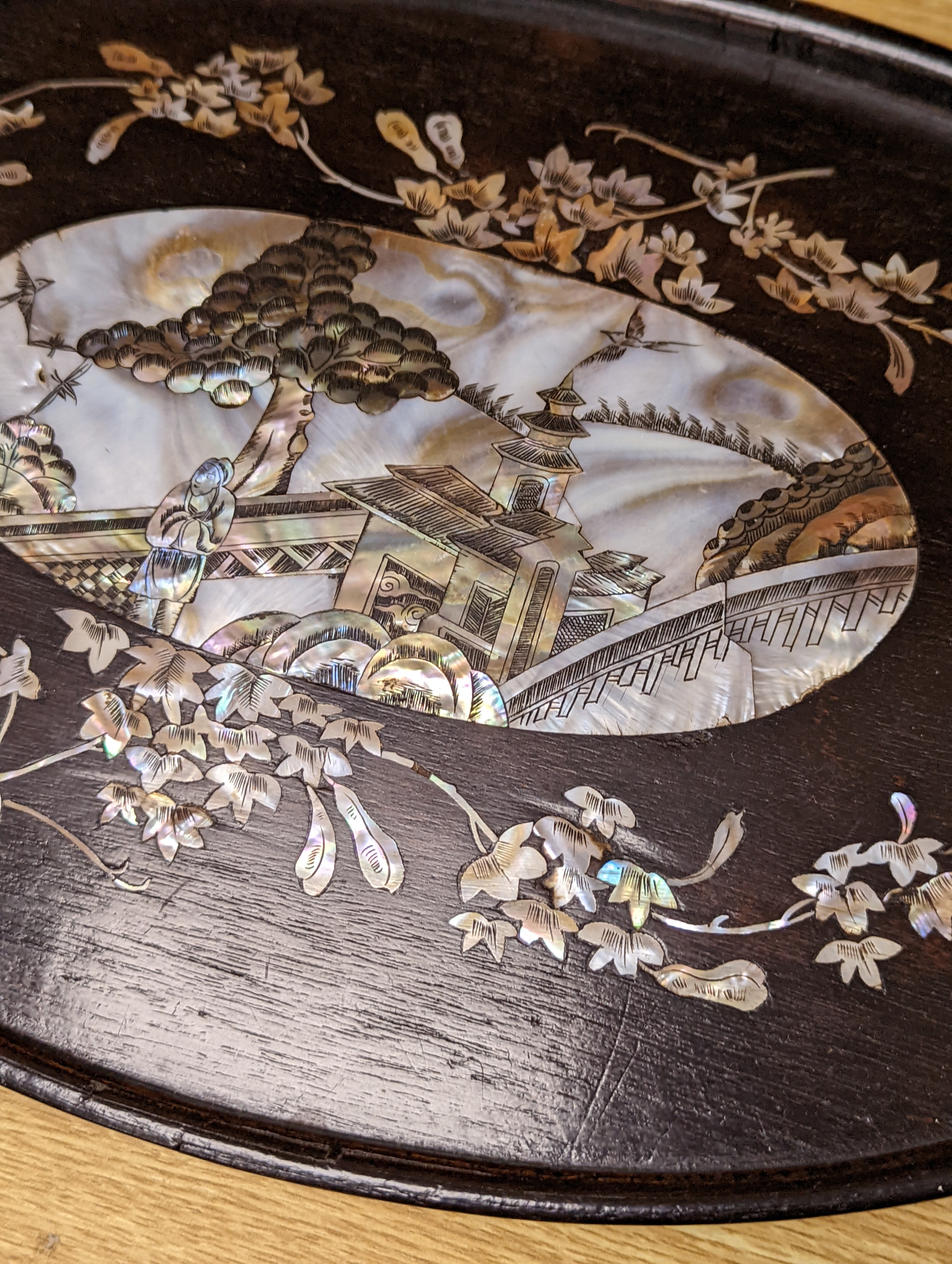 Two Chinese mother of pearl inlaid hongmu trays, the rectangular example with birds and insects amid flowers and the smaller oval example with a pavilion in a landscape within floral sprays 55x34cm
